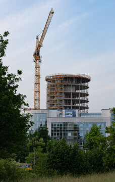 Construction site of a new round tower being build with a big crane on the left