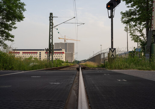 View of railroad tracks stretching far in to the horizon to a train station - Big buildings and construction on the left side - point fo view from tracks