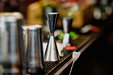 Shallow depth of field (selective focus) image with alcohol jiggers of a bartender on the counter of a bar.