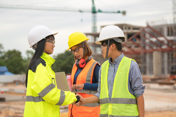 Young and senior Engineers discuss about work of large building underconstruction,Three people working on site of under construction
