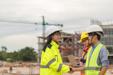 Young and senior Engineers discuss about work of large building underconstruction,Three people working on site of under construction