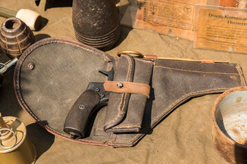 An old revolver of the Nagant system in a canvas holster lies on a demonstration table