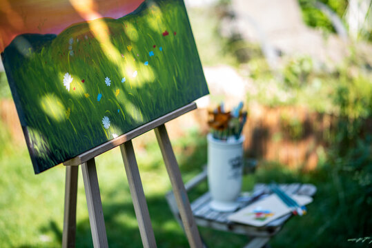 Easel with canvas art painting outdoors in a garden. Mindfulness, art therapy and creative hobbies concept.