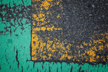 緑色と黄色い部分が古くなって不思議な模様を描いているアスファルト道路
