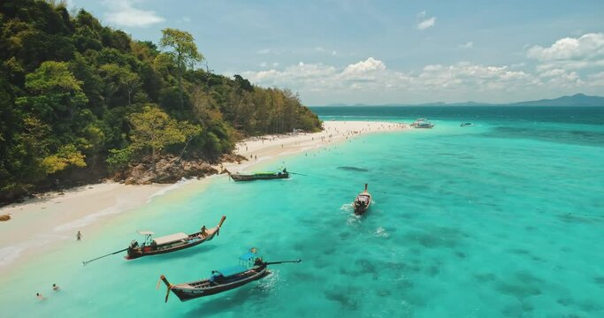 Aerial tropical island beach boat tour. Turquoise sea water. Traditional wooden long-tail boats, floating on vacation trip to paradise shore. Aamazing beautiful wild landscape in Thailand. Travel