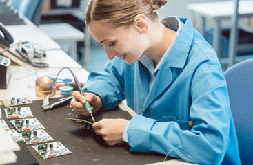 Worker in electronics manufacturing soldering a component for the prototype series by hand - obrazy, fototapety, plakaty