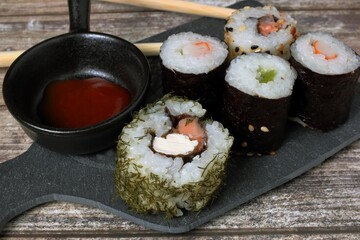 Sushi giapponese su un piccolo tagliere di pietra e fondale di legno. Messa a fuoco selettiva.