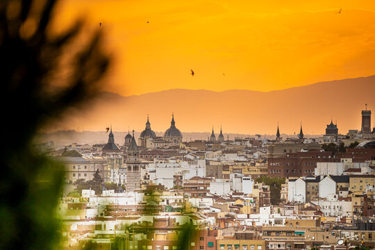 Puesta de sol en la ciudad de Madrid con vistas a los edificios y peque&ntilde;as nubes con el horizonte anaranjado, atardecer.