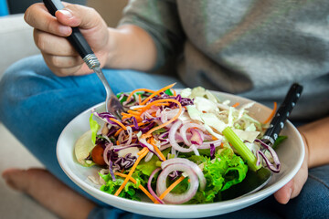 Woman Hand pricking with a fork holding bowl of fresh salad ,closeup