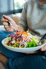 Woman Hand pricking with a fork holding bowl of fresh salad ,closeup