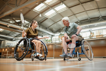 Full length portrait of disabled sports team training during badminton practice in indoor court