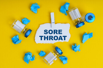 On a yellow background are ampoules, blue crumpled paper and paper with the inscription - SORE THROAT