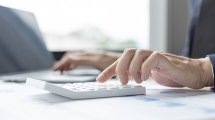Businessman presses a calculator to calculate earnings and analyze company earnings in his private office, Information in finance and accounting, Company performance and revenue.
