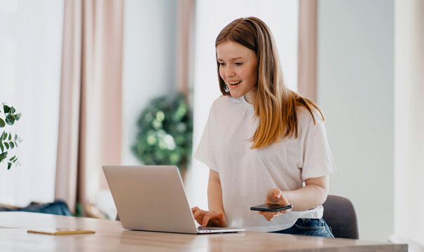 A woman of European appearance in the apartment works online on a laptop. Makes online orders on the clothing store's website. Prints a letter in the phone to an email to a friend or colleague.