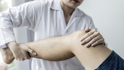 Physical therapy, Female physiotherapist treats legs and hips pain for a male patient attending in clinic, Bone arrangement, Non-surgical medical treatment, Modern medical techniques.