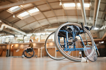 Low angle background image of sports wheelchair at indoor badminton court, copy space