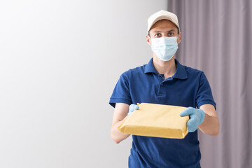 Fototapeta na wymiar Delivery guy with protective mask and gloves holding box with groceries
