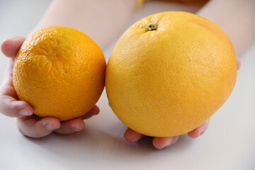 the child holds healthy fruits orange and grapefruit in his hands