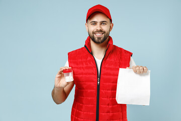 Delivery guy employee man in red cap white T-shirt vest uniform work as dealer courier tablets aspirin pills in bottle, blank paper bag isolated on pastel blue color background studio Service concept
