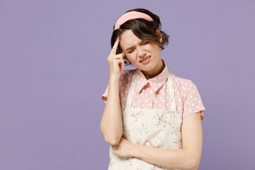 Young puzzled displeased troubled sad housewife housekeeper chef cook baker woman wearing pink apron prop up head forehead isolated on pastel violet background studio portrait. Cooking food concept - obrazy, fototapety, plakaty