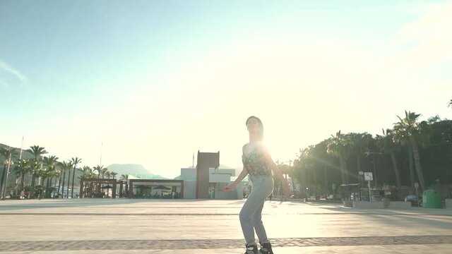 Pretty woman inlineskating along port of Cartagena with sunlight in background,Spain. Silhouette of female person rollerblading in sunset. Slow motion footage.