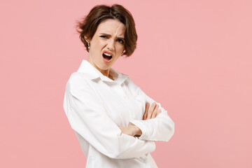 Side view young indignant sad shrewd employee business woman corporate lawyer in classic formal white shirt work in office hold hands crossed isolated on pastel pink color background studio portrait.