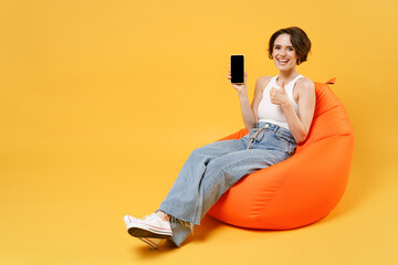 Young woman in white tank top shirt hold mobile cell phone with blank screen workspace area chat...