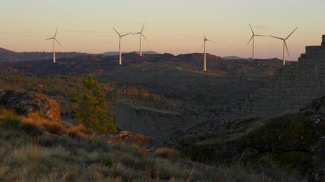 Sortelha nature landscape view with mountains, trees, boulders and wind turbines at sunset, in Portugal