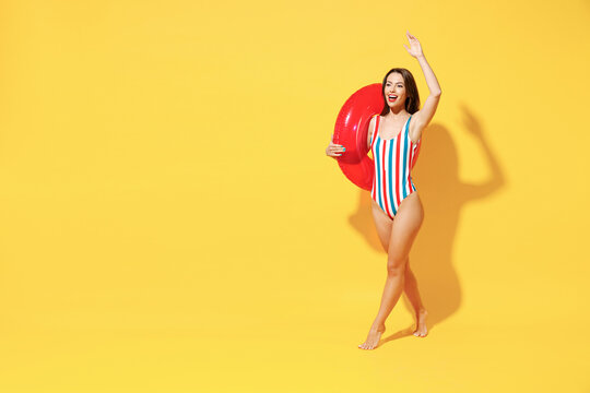 Full length fun happy young sexy woman slim body wear red blue swimsuit pose go with inflatable rubber ring isolated on vivid yellow color background studio Summer hotel pool sea rest sun tan concept