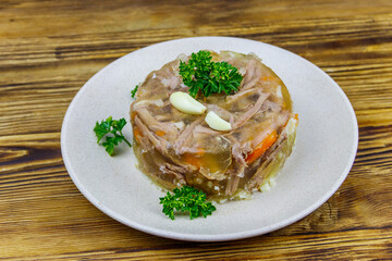 Meat aspic in a plate on a wooden table. Traditional russian dish