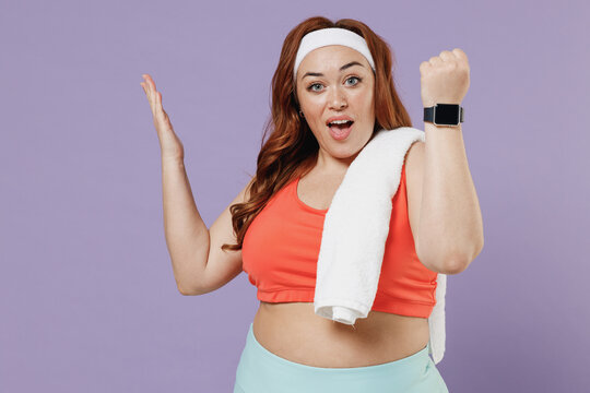 Young chubby overweight plus size big fat fit woman in red top towel warm up training show smart watch blank screen spread hand isolated on purple background home gym Workout sport motivation concept