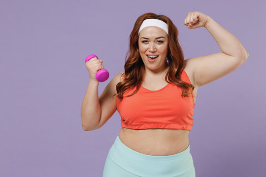 Young chubby overweight plus size big fat fit woman 20s wear red top warm up training with dumbbells show biceps muscles power isolated on purple background home gym Workout sport motivation concept.