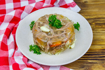 Meat aspic in a plate on a wooden table. Traditional russian dish