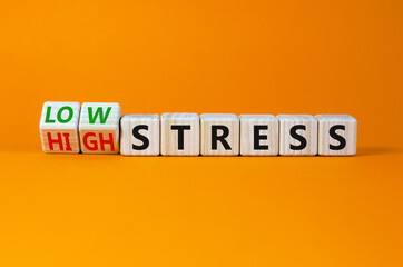 Low or high stress level symbol. Turned wooden cubes and changed words high stress to low stress. Beautiful orange background. Low or high stress level concept. Copy space.