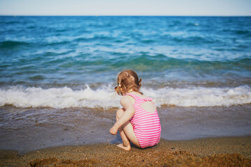 Happy little girl having fun on the beach at Mediterranean sea in France
