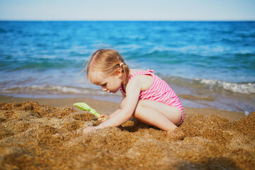 Happy little girl having fun on the beach at Mediterranean sea in France