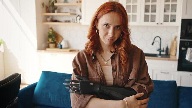 Portrait of a beautiful young amputee woman. The girl wears a bionic prosthesis on her left hand. Close up of female Disabled Person at Home in the Kitchen