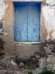 Closed blue color wooden windows on the old plaster peeling stone wall