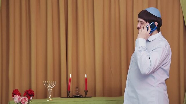Before the chuppah ceremony, the Jewish groom speaks on the phone in the synagogue hall