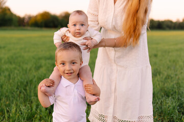 Fototapeta premium Traditional family in light clothes in the field nature. Walk at sunset. Christians. priest with his wife and childrens are happy together. Positive parenting. Siblings brother and sister childhood