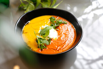 Yellow creamy pumpkin and carrot soup. Dietary yellow vegetable soup.
Dish on a plate, food photography, serving proposal.