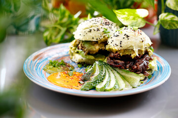 Sandwich with vegetables, fried red onion and avocado salad served with fresh cucumber and humus.
Dish on a plate, food photography, serving proposal.