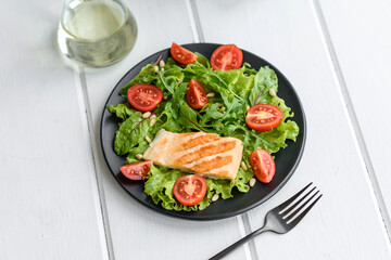Delicious fresh salad with fish, tomatoes and lettuce leaves