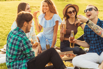 group of friends who make a picnic in nature, eat pizza and drink drinks, Happy people have fun on a picnic in the countryside on the grass