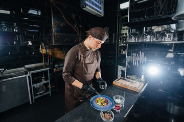 A professional chef prepares a delicious fresh salad of green vegetables and juicy veal in a modern and stylish restaurant. Cooking in a restaurant.