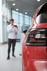 Vertical cropped shot of selective focus on car lights, man taking photo of an automobile on...