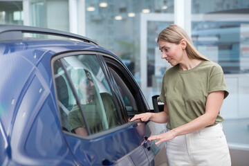 Fototapeta na wymiar Female customer examining auto for sale at car dealership