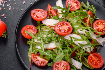 Pieces of chicken, tomatoes and lettuce leaves on a dark concrete background