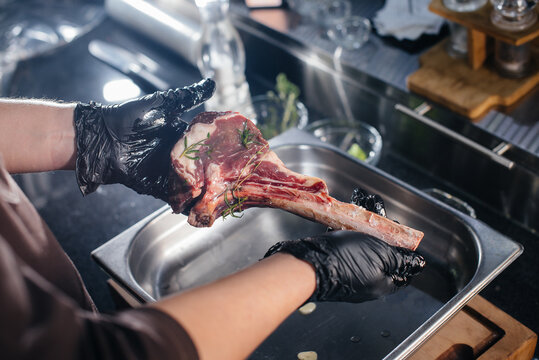 A professional chef marinates and prepares a juicy steak from a fresh piece of meat. Cooking in an mca in a gourmet restaurant.
