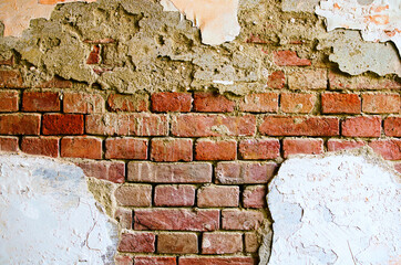 Old red brick wall. Painted distressed wall surface. Grungy brickwall. Grunge red stonewall. Shabby building facade with damaged plaster. Abstract background. Textured suface. Chernivtsi, Ukraine